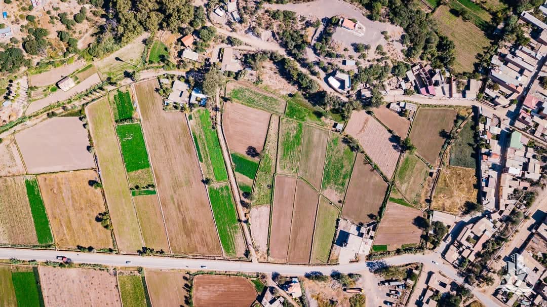 Top aerial view of the land and its proximity to homes, crops and paved road